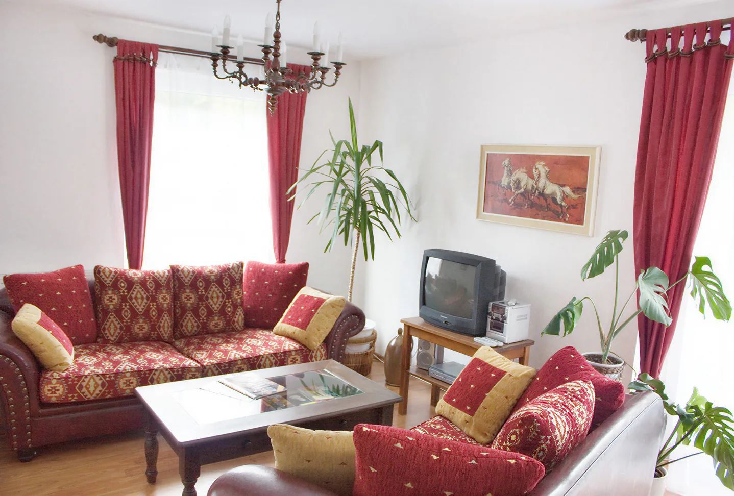 Wohnstube der Wohnung 1 mit roten Sofas und Sat-TV